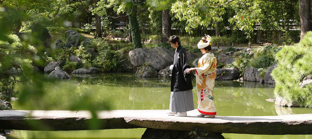 清澄庭園にかかる橋を手を引き歩く新郎新婦