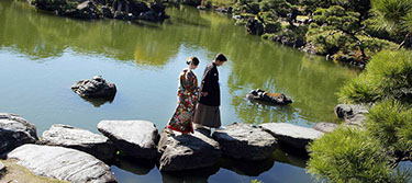 枯山水の飛び石を手を繋いで歩く新郎新婦